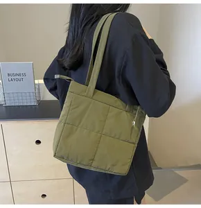 Detail shot of olive green quilted tote bag showing padded texture and strap on a model