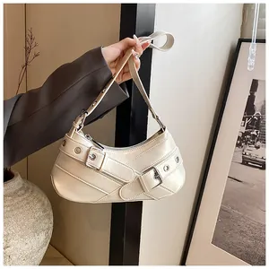 Detail shot of beige faux leather underarm bag with silver buckles and eyelet straps