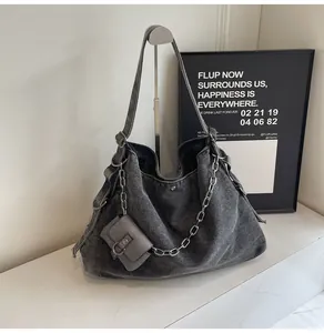 Macro shot of large denim tote bag featuring side ruffles and metal chain detail