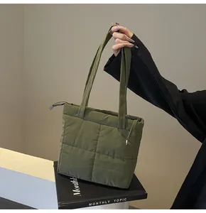 Close-up of olive green quilted puffer bag featuring refined stitching and top zipper