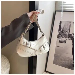 Close-up of off-white shoulder bag with metallic buckles and punk-style eyelet details