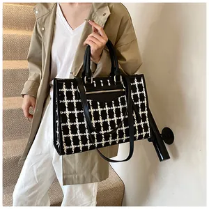 Detail of black and white tweed tote bag featuring gold hardware and elegant texture