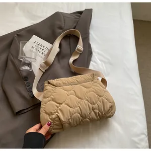 Detail of wave quilted pattern and adjustable wide strap on khaki padded crossbody bag