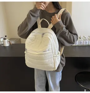 Nahaufnahme eines weißen gesteppten Rucksacks mit silbernen Reißverschlüssen und Seitentaschen