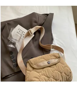 Detail of khaki quilted crossbody bag with adjustable strap on a stylish blazer