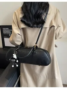 Retro black leather baguette shoulder bag with plush charm on khaki trench coat
