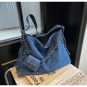 Detail of blue denim tote bag with silver metal chain and matching mini pouch on side
