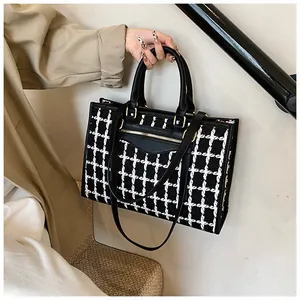 Detail of tweed houndstooth tote bag with leather trim and adjustable shoulder strap