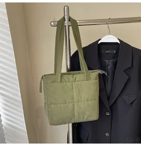 Detail of olive green quilted puffer tote bag with square stitching and top zipper
