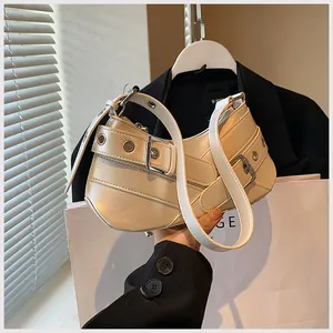 Detailed close-up of beige leather shoulder bag with silver metal studs and eyelets