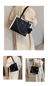 Detail of black leather tote with white faux shearling trim and golden chain accessory