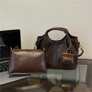 Deep brown matte leather bucket bag set with laptop on glass desk for office use