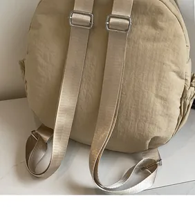 Detail of adjustable shoulder straps with silver metal buckles on a canvas backpack