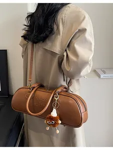 Brown leather boston cylinder bag with brand embossing and plush charm accessory