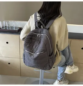 Detail eines grauen gesteppten Nylonrucksacks mit Wellennähten und gepolsterter Textur