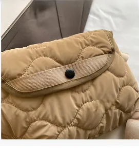 Close-up of khaki quilted crossbody bag with wavy texture and black snap button closure