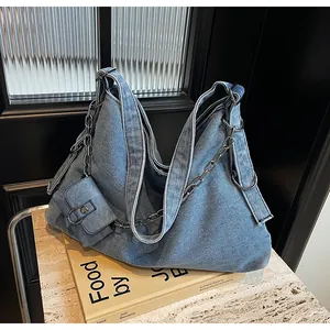 Detail shot of light blue denim hobo bag with metal chain strap and small pouch