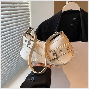 Close-up of cream underarm bag featuring silver buckles and textured faux leather
