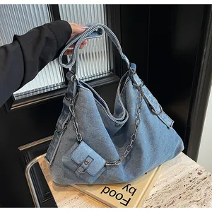 Detail view of denim hobo bag with thick metal chain and mini matching pouch attachment