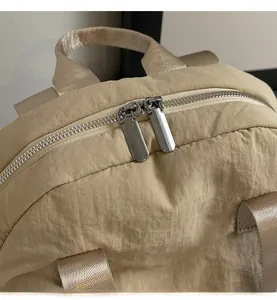 Close-up of smooth dual metal zippers and durable woven handle on beige canvas backpack