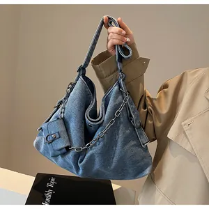 Detail of blue denim tote bag with silver chain and mini pouch on model's hand
