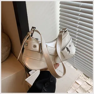 Detail of a chic cream hobo bag with adjustable buckle straps and metallic eyelets