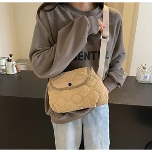 Detail of beige quilted crossbody bag featuring wave patterns and a black round buckle