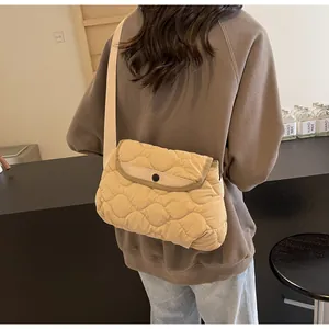 Quilted beige puffer crossbody bag shown on a model with wave texture and strap detail