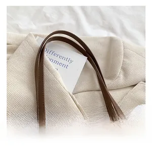 Detail of the stitched leather strap and white plush trim on a brown tote shoulder bag