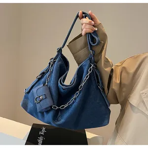 Detailed view of blue denim tote bag with thick silver chain and mini purse accessory
