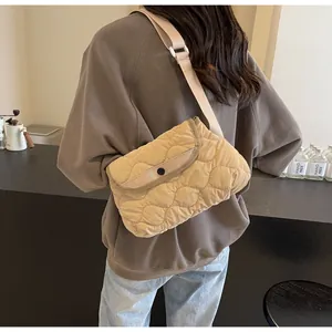 Detail of wave-quilted beige crossbody bag featuring adjustable strap and buckle