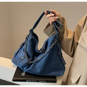 Detail of blue denim tote bag featuring silver metal chain and small matching pendant pouch