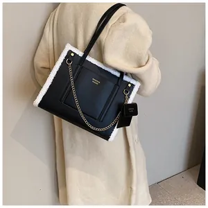 Detail of black faux leather tote with white plush trim and golden chain strap detail