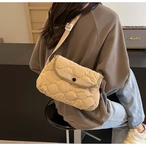 Close-up of beige quilted crossbody bag showing soft wavy stitching and flap buckle detail