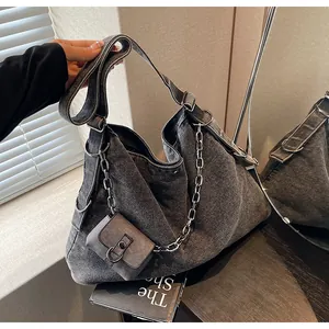 Detailed close-up of dark denim bucket bag with large silver chain and small coin pouch