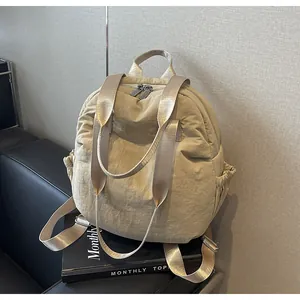 Detail of beige nylon travel backpack showing water-resistant fabric and side pocket