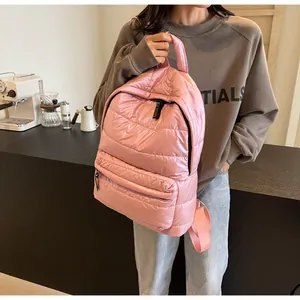 Detail of pink padded quilted backpack showing puffy fabric and front zipper pocket