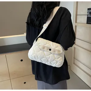 Rear view of a white quilted crossbody puff bag with adjustable wide strap on a model