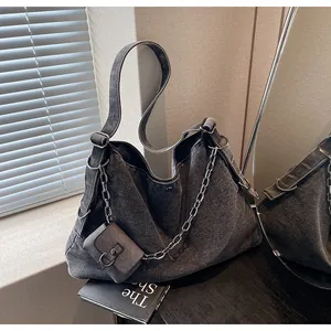 Detail of grey denim tote bag with metal chain strap and matching small pouch