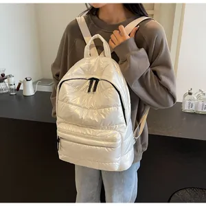 Close-up of shiny white quilted backpack made of puffy padded waterproof nylon fabric