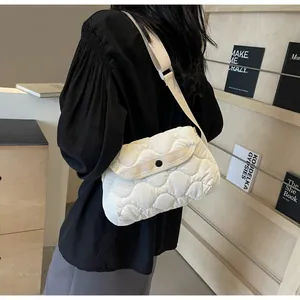 Detailed view of white quilted padded crossbody bag with wave texture and adjustable strap
