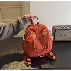 Close-up of orange waterproof backpack featuring dual zippers and adjustable straps