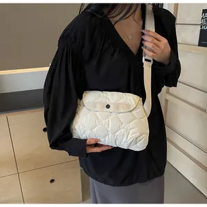 Detailed view of white quilted shoulder bag with wave stitching and adjustable strap