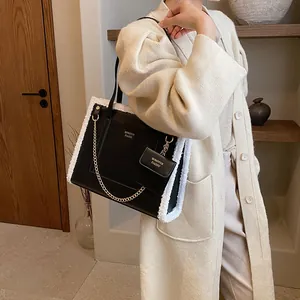 Black leather tote bag with white faux fur trim and gold chain detail for autumn