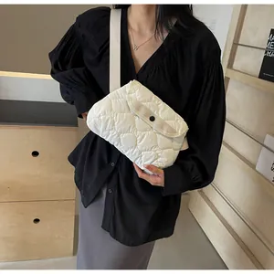 Close-up of white quilted cloud crossbody bag with soft texture and black button closure