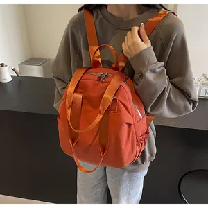 Detailed view of orange nylon travel backpack featuring side elastic pockets and metal zippers