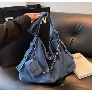 Macro detail of large denim hobo bag featuring silver chain and matching mini pouch