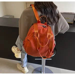 Detailed view of the bright orange nylon travel backpack with textured fabric and straps