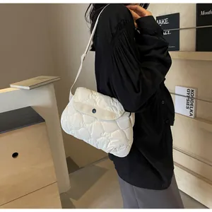 Detailed view of white quilted crossbody cloud bag featuring a black snap button closure