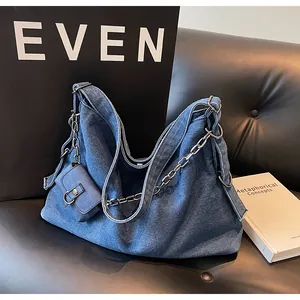 Detailed shot of dark blue denim tote bag with silver chain strap and mini purse on a chair